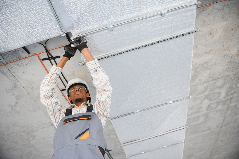 Construction worker installing a ventilation system, focusing on energy efficiency and insulation solutions for homes and businesses in Perth, Western Australia.