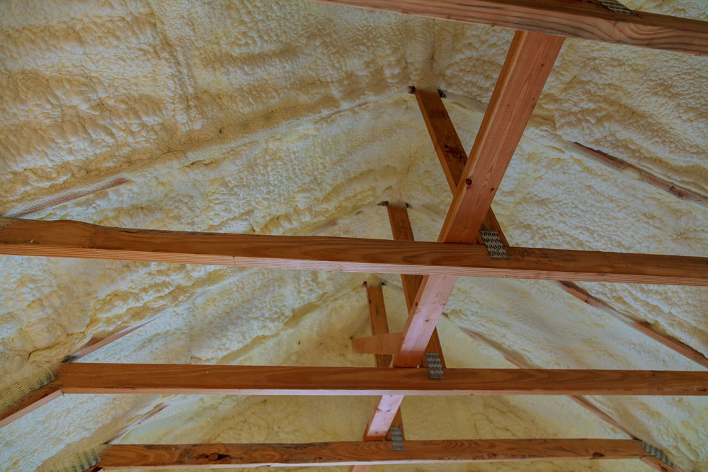 Underfloor spray foam insulation applied to wooden beams, showcasing energy-efficient insulation solutions for buildings in Perth.