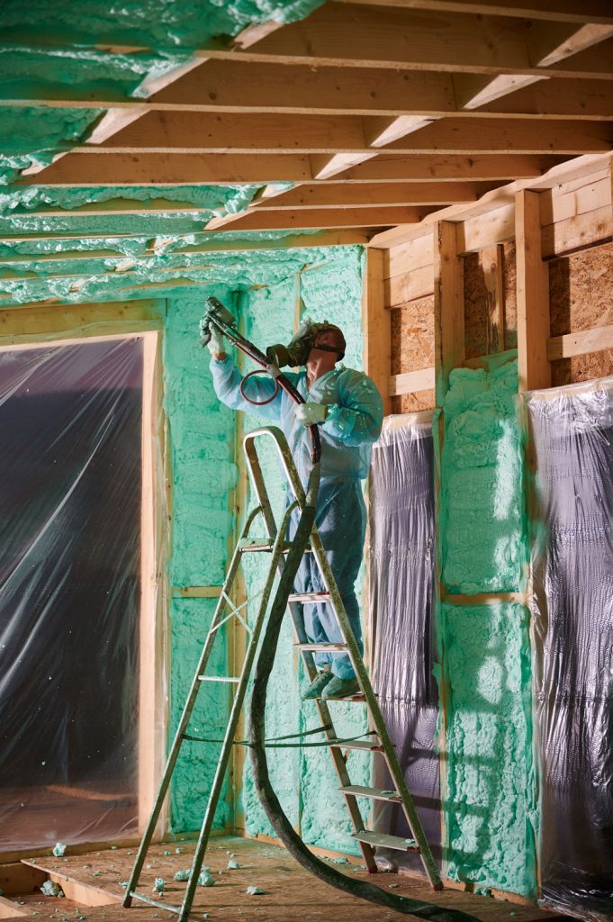 Worker applying spray foam insulation in a building, enhancing energy efficiency and comfort in Perth, with a focus on eco-friendly solutions.